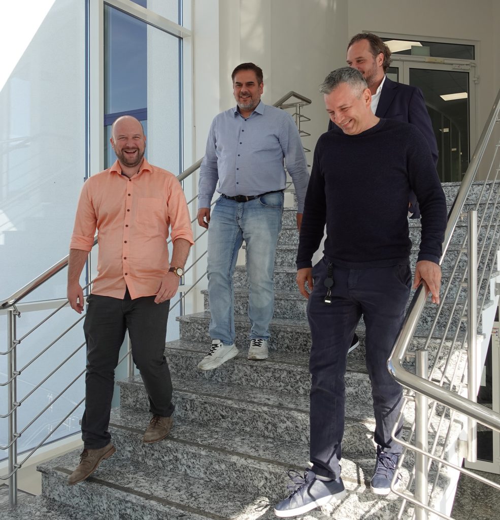 Das TKD Management geht auf dem Bild die Treppe herunter. Alle sind glücklich und lächeln. Es fehlen Oliver Torlee und Chris Bordeu.